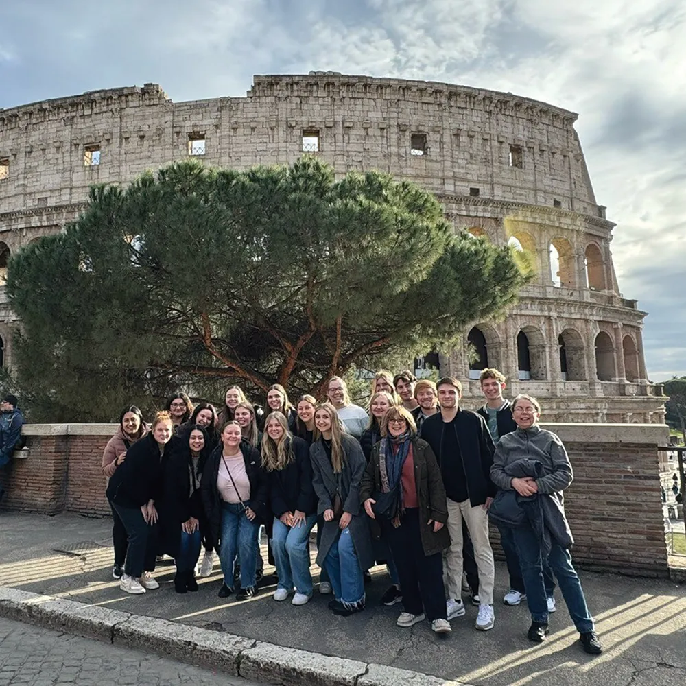 Group photo of people in front of the Colosseum in Rome.