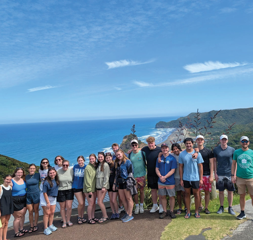 Group of people posing on a scenic overlook with ocean and coastline in the background.