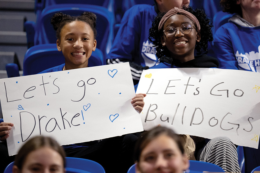 Two people holding supportive signs for a team in a sports arena.