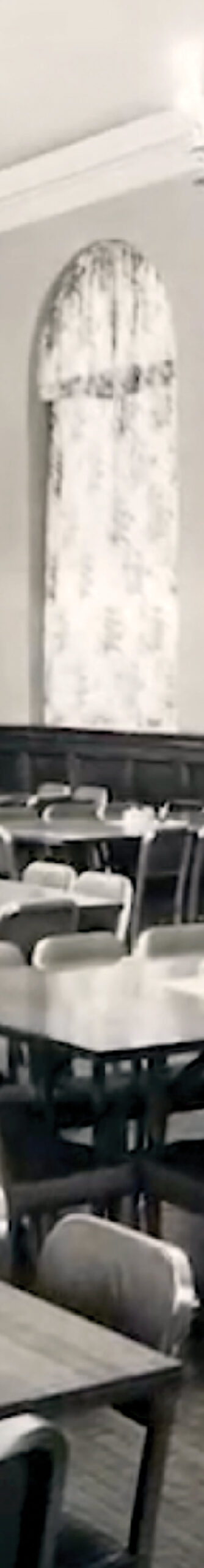 A dining room with tables, chairs, and a large curtained window.
