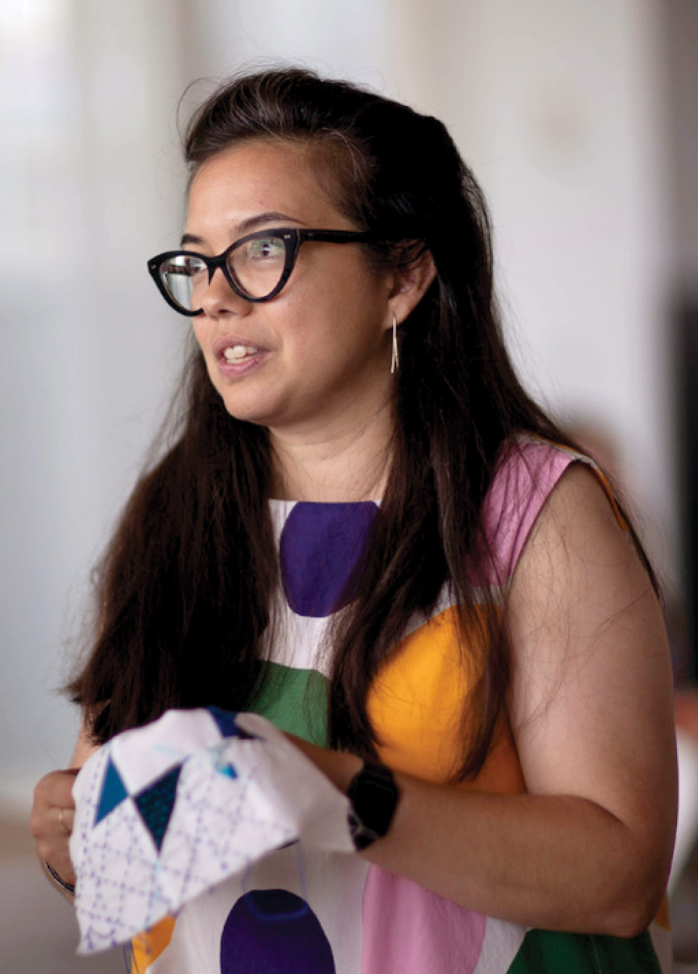 Woman with glasses holding a patterned fabric.