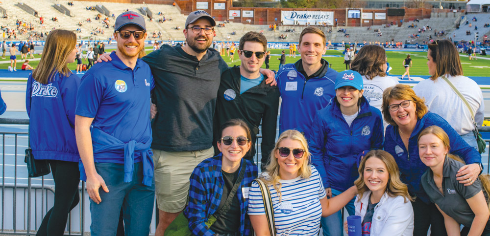 Group of ten people posing in a stadium, wearing casual blue-themed clothing.