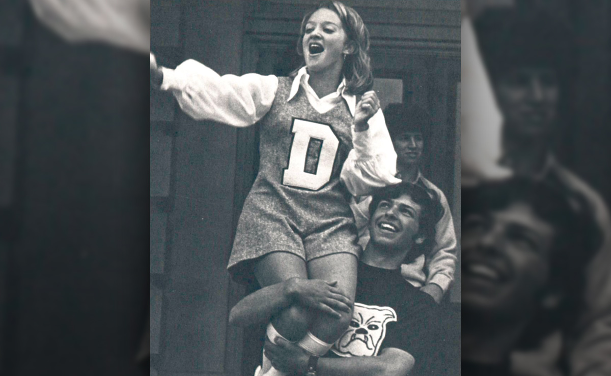 A young woman on a man's shoulders, wearing a sweater with the letter "D".