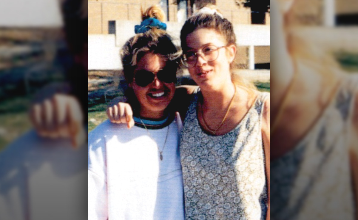 Two people smiling and posing outdoors with arms around each other.