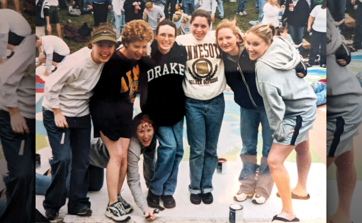 A group of seven people posing and smiling outdoors at a painting event.