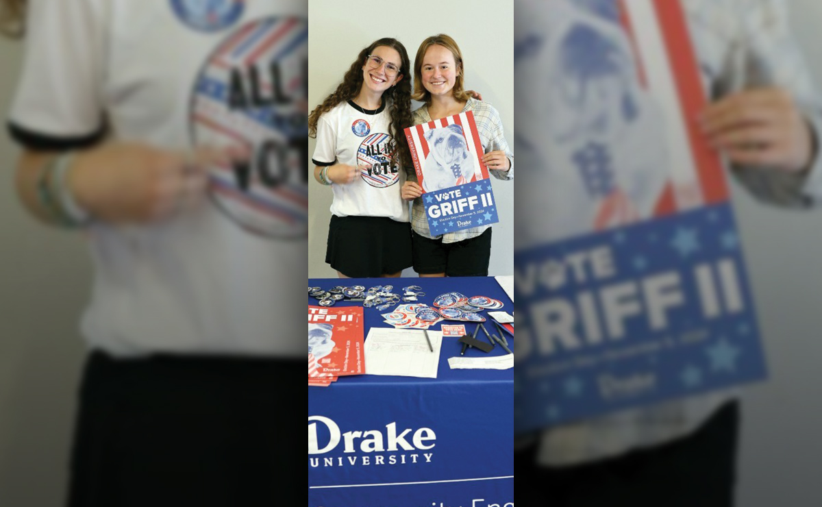 Two people at a table with Drake University materials and a "Vote Griff II" poster.