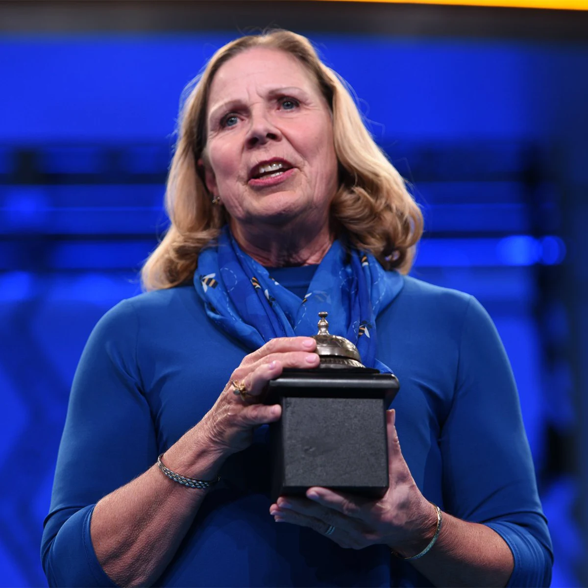 Mary Brooks wearing all blue and holding a bell.