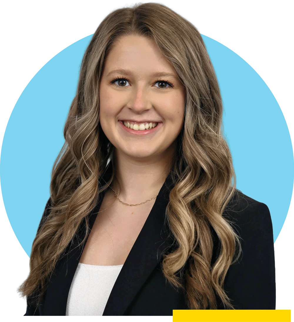 Professional headshot of Kayla Hruska with long, wavy blonde hair wearing a black blazer and white top, set against a light blue circular background.