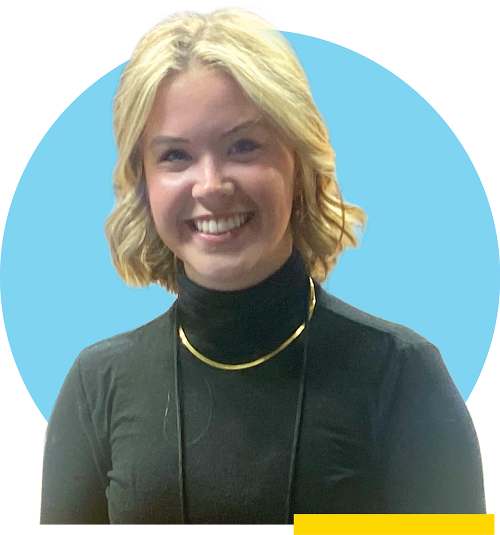 Mel Dygert wears a black turtleneck and a gold necklace, set against a light blue circular backdrop.