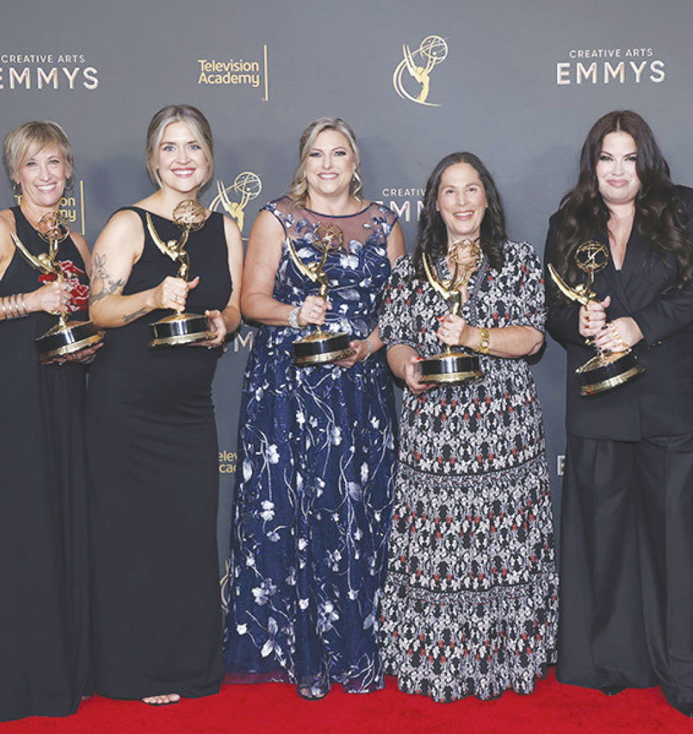 Michele "Mickie" A. Paskal and others hold Emmy awards while posing together on a red carpet in front of a Creative Arts Emmys backdrop.