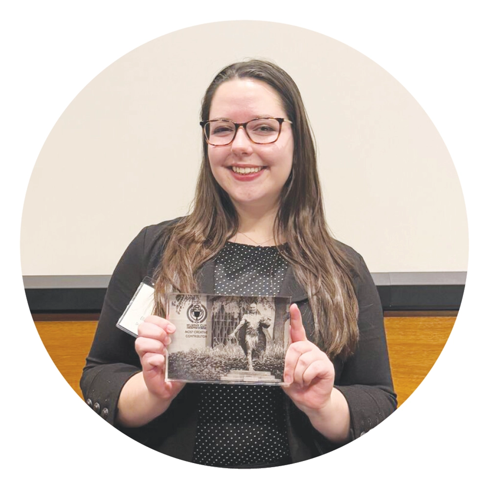 Ella Rother holds up a small rectangular plaque award.