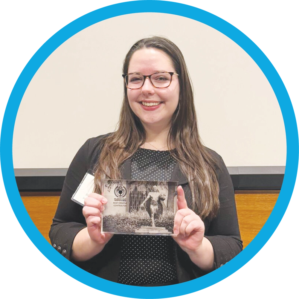 Ella Rother holds up a small rectangular plaque award.