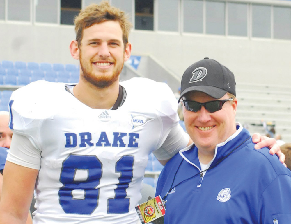 A football player wearing a white Drake jersey number 81 poses with a smiling man in a blue jacket and hat.