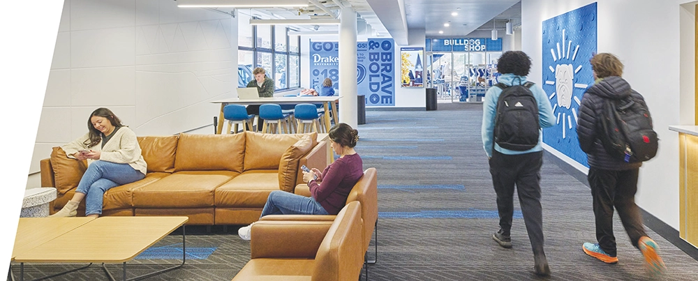 Students relax on leather sofas and walk through a modern campus building hallway.