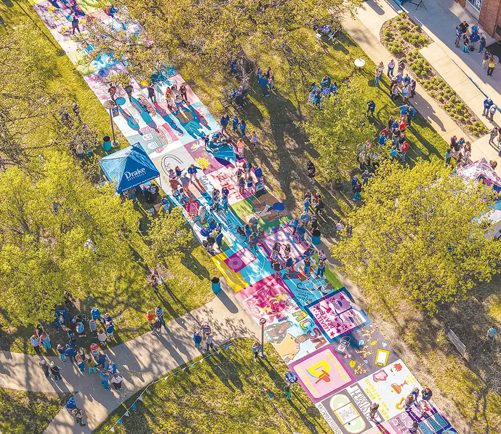 High aerial view of a painted campus walkway crowded with people attending an outdoor festival.